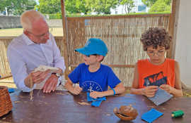 Wolfram Leibe unterhält sich mit zwei Kindern in der Schneiderwerkstatt der Spielstadt