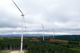 Luftbild von drei Windrädern in einem Waldgebiet