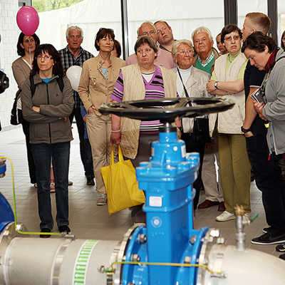 Eine Besuchergruppe steht vor den großen Leitungen im Pumpwerk. Dort gelangt das Wasser zur Aufbereitung in die Membranfilter. Foto: SWT