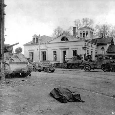 Am 2. März 1945 bewachen Panzer und Schützenpanzer der 10. US-Panzerdivision die kurz zuvor eroberte Römerbrücke. Im Vordergrund liegt ein toter deutscher Offizier. Foto: Stadtarchiv