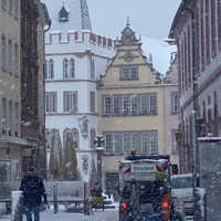 Schneegestöber vor historischen Gebäuden und ein Räumfahrzeug