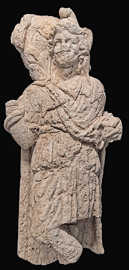 Zu sehen ist ein Stück von einem Kalksteinrelief, das einen Menschen darstellt. Das Relief ist bis zu den Knien der dargestellten Person erhalten.