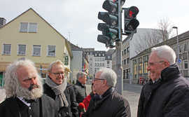 OB Wolfram Leibe, Baudezernent Andreas Ludwig und Zeichner Johannes Kolz freuen sich über den gelungenen Start der neuen Ampelmännchen am Simeonstiftplatz.