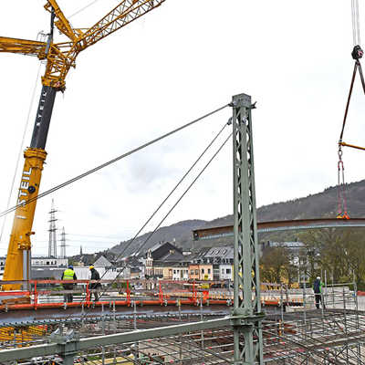 36 Tonnen hängen an: Ein weiteres gewölbtes Stahlträgerelement für den Überbau der Eisenbahnüberführung in Trier-West wird vom Liebherr-Mobilkran eingehoben.