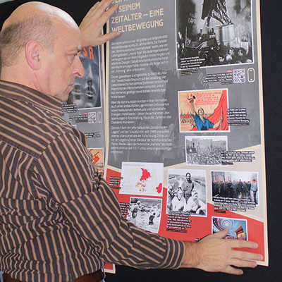 VHS-Leiter Rudolf Fries testet im Foyer die Positionierung eines Plakats für die neue Ausstellung. QR-Codes ermöglichen es den Besuchern, sich vertiefend über einzelne Schwerpunkte zu informieren. 