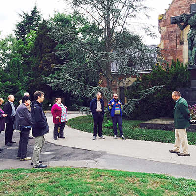 Heinz Tholl vom Grünflächenamt (rechts) erläutert einer Gruppe das Außengelände der alten Kapelle auf dem Hauptfriedhof in Trier-Nord. Foto: Trier-Gesellschaft
