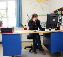 Foto: Am blauen Schreibtisch nimmt Mitarbeiterin Sabrina Anfragen per E-Mail oder Telefon entgegen.