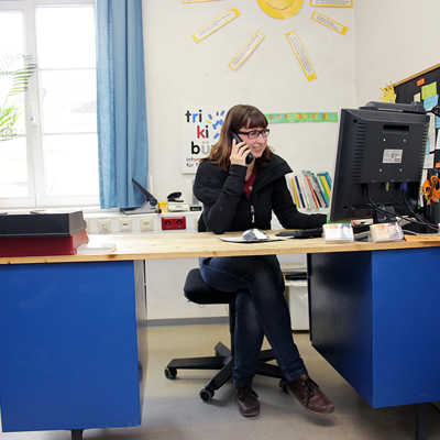 Am blauen Schreibtisch nimmt Mitarbeiterin Sabrina Anfragen per E-Mail oder Telefon entgegen.