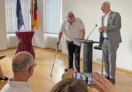 Wolfram Leibe und Harald Michels stehen in einem mit Fahnen geschmückten Saal vor einem Rednerpult