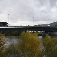 Pkws und Lkws befahren eine Brücke über einen breiten Fluss