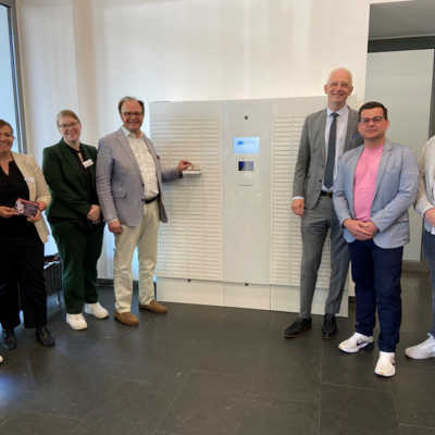 Oberbürgermeister Wolfram Leibe (3. v. r.) und Dezernent Ralf Britten (4. v. l.) testen mit den Chefinnen des Bürgeramts, Maylin Müllers (2. v. l.) und Julia Borens (3. v. l.) sowie weiteren Beteiligten die neue Dokumenten-Ausgabebox im Rathaus am Augustinerhof. Diese enthält 304 Fächer für Ausweise und Reisepässe.