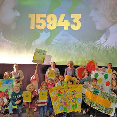 Bei der Abschlussveranstaltung der Kindermeilen-Kampagne im Broadway-Kino präsentieren die Kinder Bürgermeisterin Elvira Garbes (hinten links) ihre selbstgebastelten Plakate. Foto: Lokale Agenda 21