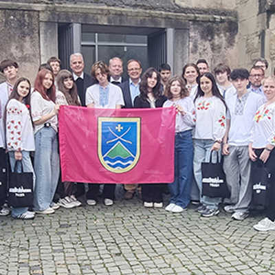 Nach dem Empfang im Rathaus mit Beigeordnetem Ralf Britten und Weihbischof Jörg-Michael Peters (hinten Mitte) sowie Vertretern der deutsch-ukrainische Vereine präsentieren die Jugendlichen aus Isjum beim Gruppenfoto die Flagge ihrer Heimatstadt. 