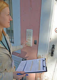 Eine Frau betätigt eine Klingel an einer Haustür.