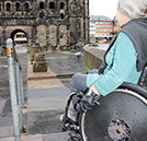 Heike Unterrainer mit ihrem Rollstuhl vor der zu steilen Rampe an der Porta, an die sich ein Sockel (Bildmitte) anschließt. Jetzt ist Besserung in Sicht.