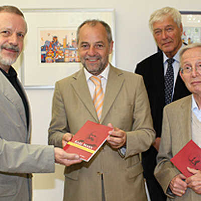 Dr. Erwin Otto (Wissenschaftlicher Verlag Trier), Ignaz Bender und Heinz Monz (v. l.) stellen OB Klaus Jensen die erweiterte Neuauflage des Karl-Marx-Buchs vor.
