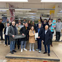 Die Vertragspartner und Vertreter der Skateszene stehen auf einer Rampe in der Skatehalle und freuen sich über die Einigung