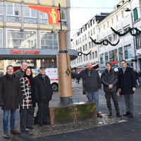 Gruppenbild von sieben Personen in Winterjacken am Pranger in der Grabenstraße