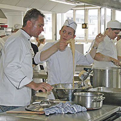 Lehrlinge aus Trier und Metz kochen gemeinsam in der Schulküche der Berufsbildenden Schulen: Während vorne frische Spätzle zubereitet werden, dampft dahinter der Topf mit Rotkohl.