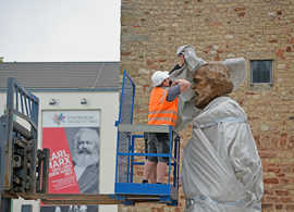 Für die Medien wird kurz der Kopf der Marx-Statue freigelegt, bevor Arbeiter ihn wieder sorgfältig verhüllen. 