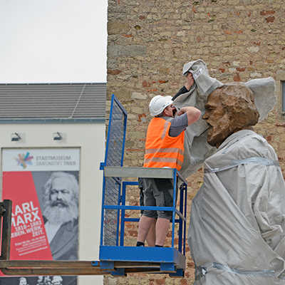 Für die Medien wird kurz der Kopf der Marx-Statue freigelegt, bevor Arbeiter ihn wieder sorgfältig verhüllen. In Gänze ist der Bronze-Marx ab 5. Mai zu sehen. Foto: Dieter Jacobs