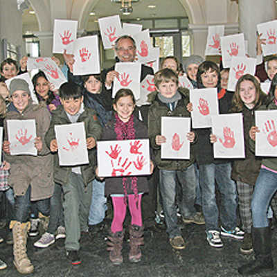 chülerinnen und Schüler des AVG, der Grundschule Kenn und Kinder der Kita Sirzenich übergeben Klaus Jensen (Mitte) die Zettel mit den Handabdrücken.
