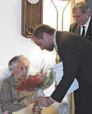 Mit einem Blumenstrauß in den Stadtfarben Gelb und Rot gratuliert OB Klaus Jensen Margarete Kollmann zu ihrem 102. Geburtstag. Rechts ihr Sohn, Pfarrer Klaus Kollmann.