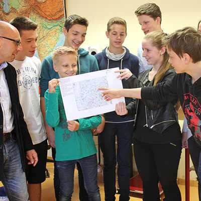 Lehrer Andreas Lohr (links) und seine Schüler aus den Jahrgangsstufen 8 bis 10 diskutieren über einen Entwurf für einen ihrer Stadtpläne.