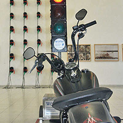 Zwischen den Kunstwerken, darunter eine Installation mit Benzinkanistern und mehreren Fotos (im Hintergrund), wurde dieses Motorrad in der Kunsthalle „geparkt“.
