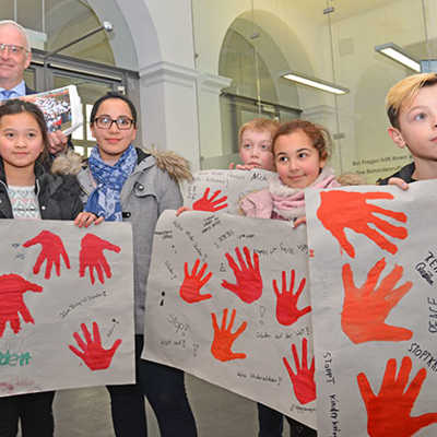 Schülerinnen und Schüler der Matthias-Grundschule präsentieren ihre Handabdrücke, bevor sie diese OB Wolfram Leibe (hinten l.) übergeben, der sie an Bundesjustizministerin Dr. Katarina Barley weiterleitet.