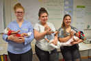 Drei Teilnehmerinnen des ersten Praktikums an der IGS mit ihren Baby-Simulationspuppen. Das Füttern spielt im Test-Tagesablauf eine zentrale Rolle. Foto: Johanniter/Regina Lüders