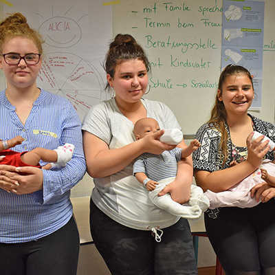 Drei Teilnehmerinnen des ersten Praktikums an der IGS mit ihren Baby-Simulationspuppen. Das Füttern spielt im Test-Tagesablauf eine zentrale Rolle. Foto: Johanniter/Regina Lüders