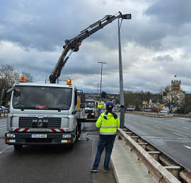 Ein mobiler Kran zieht Straßenleuchten aus ihrer Verankerung auf der Brücke