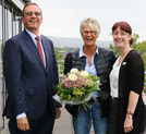 Kundenberaterin Silke Kinzig (r.) und Vorstandsmitglied Günther Passek gratulieren Kornelia Brand auf der Terrasse des Sparkassen-Gebäudes mit einem Blumenstrauß zu ihrem Gewinn. Foto: Sparkasse