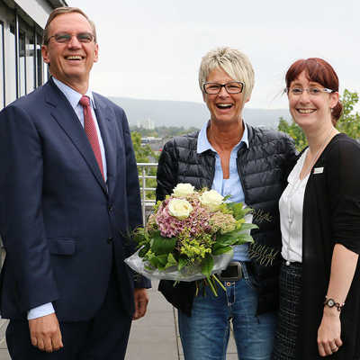 Kundenberaterin Silke Kinzig (r.) und Vorstandsmitglied Günther Passek gratulieren Kornelia Brand auf der Terrasse des Sparkassen-Gebäudes mit einem Blumenstrauß zu ihrem Gewinn. Foto: Sparkasse