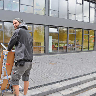 Sebastian Barth von der Umzugsfirma Knaf bringt Mobiliar in die Klassenräume des erweiterten Schulgebäudes am Estricher Weg. Der Anbau besticht durch seine Glasfassade.