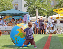 Ein Kind rollt einen Glbus-Ballon über einen grünen Teppich