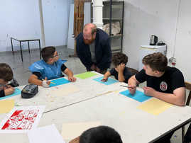 Dezernent Markus Nöhl spricht mit Schülern in der Europäischen Kunstakademie, die gerade an einem Tisch malen.