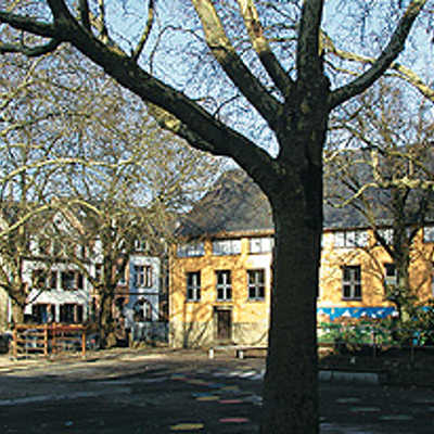 Blick auf den Schulhof, der mitten im Barbara-Viertel liegt. Gegenüber der gelb und rot angestrichenen Grundschule liegt die Montessori-Schule.