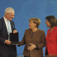 Wolfram Leibe nimmt das Münzenset von Bundeskanzlerin Angela Merkel in Empfang. Rechts Ministerpäsidentin Malu Dreyer.