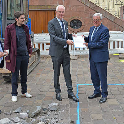 Beim Ortstermin mit Baudezernent Andreas Ludwig (l.) und MdL Sven Teuber (2. v. l.) in der Liebfrauenstraße überreicht Innenminister Roger Lewentz (r.) den Förderbescheid für die erste Zone des urbanen Sicherheitskonzepts an OB Wolfram Leibe (2. v. r.). Die gelben Punkte auf dem Pflaster markieren die Standpunkte der Poller.