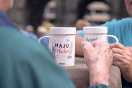 Zwei weiße Krüge mit der aufschrift "Maju-Becher" stehen auf  eine Plattform