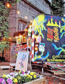 Ein umfunktionierter Bauwagen mit Theke und vielfarbigen Graffiti