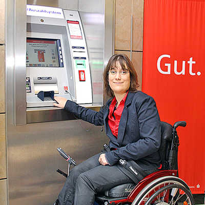 Eine Rollstuhlfahrerin bedient einen der umgerüsteten Geldautomaten. Foto: Sparkasse