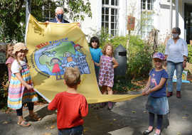 Mehre Kinder und Oberbürgermeister Wolfram Leibe zeigen eine Fahne vor dem Rathaus. Die Fahne macht Werbung für die Rechte der Kinder