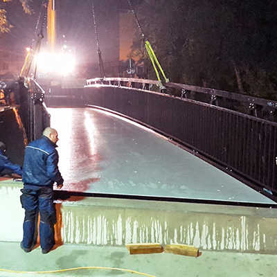 Während der Zugfahrpause in der Nacht zum Sonntag wird der neue Überbau der Hermesbrücke per Kran auf die Widerlager gelegt. Mitarbeiter der Firma PML überwachen die Prozedur. Foto: Tiefbauamt