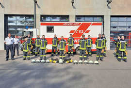 Gruppenbild: Die zwölf neuen Atemschutzgeräteträger stehen in Feuerwehrmontur gemeinsam mit ihren Ausbildern und Lehrgangsleitern vor dem Atemschutz-Fahrzeug der Feuerwehr Trier.
