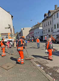 Straßenreiniger mit orangefarbener Arbeitskleidung im im Einsatz
