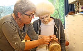 Maskenbildnerin Birgit Molitor zeigt dem bereits geschminkten Ben, wie im Theater Haarteile geknüpft werden