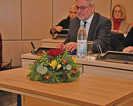 Ein Blumengesteck im Ratssaal erinnert an Jürgen Backes. Rechts im Hintergrund ist das neue Ratsmitglied Heike Franzen zu sehen.